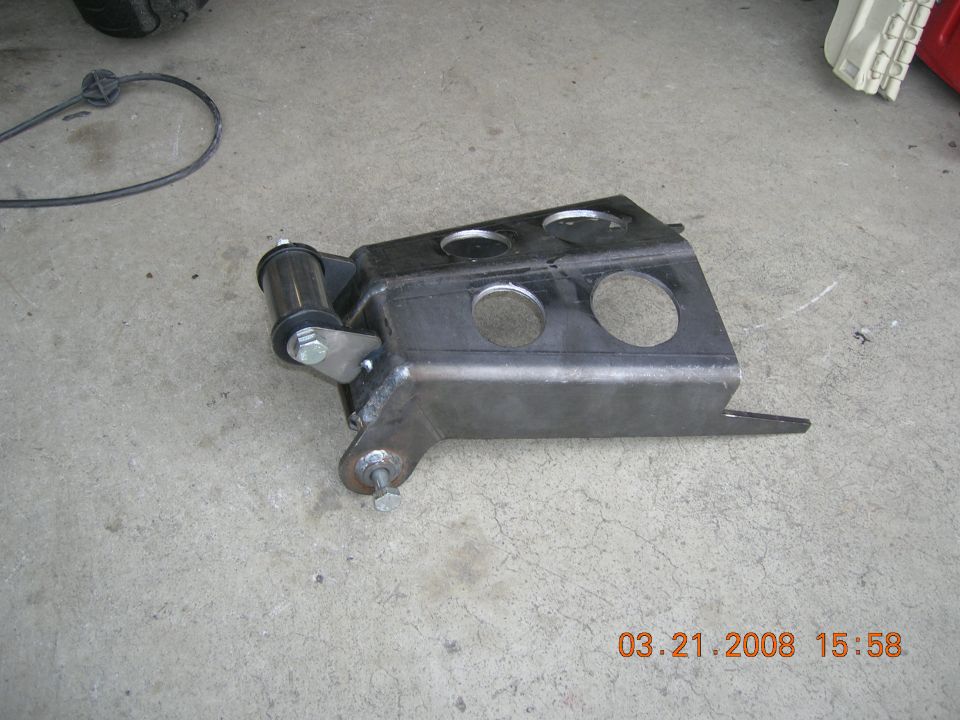 Custom fabricated metal bracket with holes and a bushing assembly, resting on a concrete surface