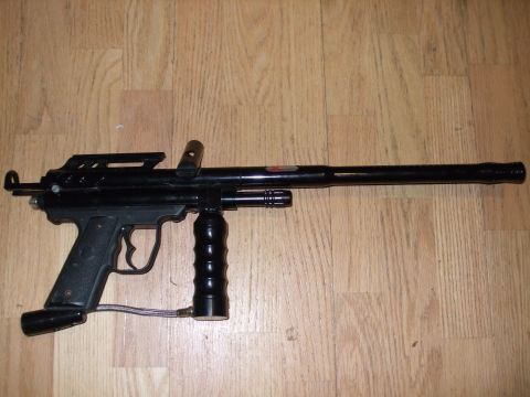 1988 Ford Bronco - A black paintball gun is shown on a wooden surface, with a visible hose connected to the grip.