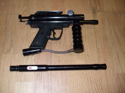 1988 Ford Bronco - A black paintball gun and its barrel are displayed on a wooden floor.