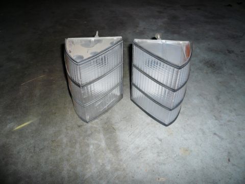 1975 Ford Ranchero - Two clear plastic tail lights with black trim are shown on a concrete surface.