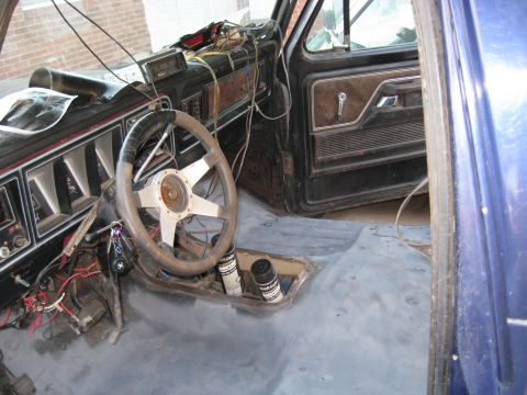 1978 Ford Bronco - The interior of a 1978 Ford Bronco shows a worn dashboard and steering wheel, with exposed wiring and a bare metal floor.