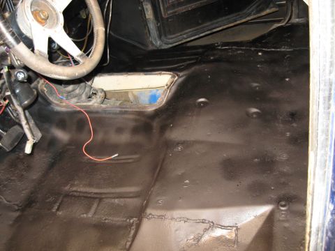 1978 Ford Bronco - The interior floor of a 1978 Ford Bronco has been coated in black undercoating, revealing the steering wheel and shifter.