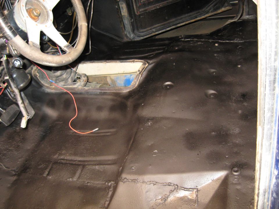 1978 Ford Bronco interior floor with black undercoating, showing steering wheel, shifter, and exposed wiring