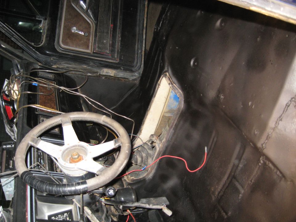 Interior view of a vehicle showing a steering wheel, dashboard, and exposed wiring