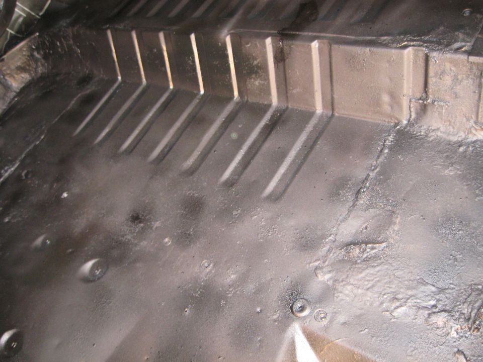 Vehicle interior floor with black undercoating and ribbed metal sections