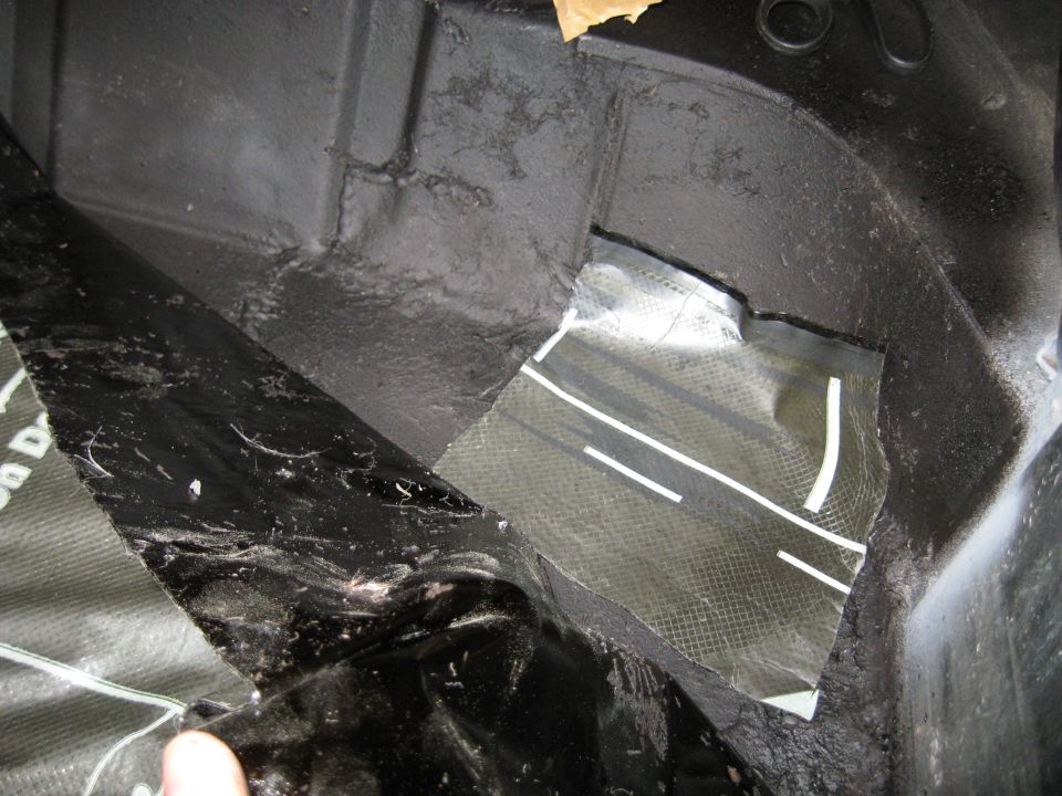 Black interior of a vehicle cargo area with sound deadening material and a patch of carbon fiber fabric with white stripes