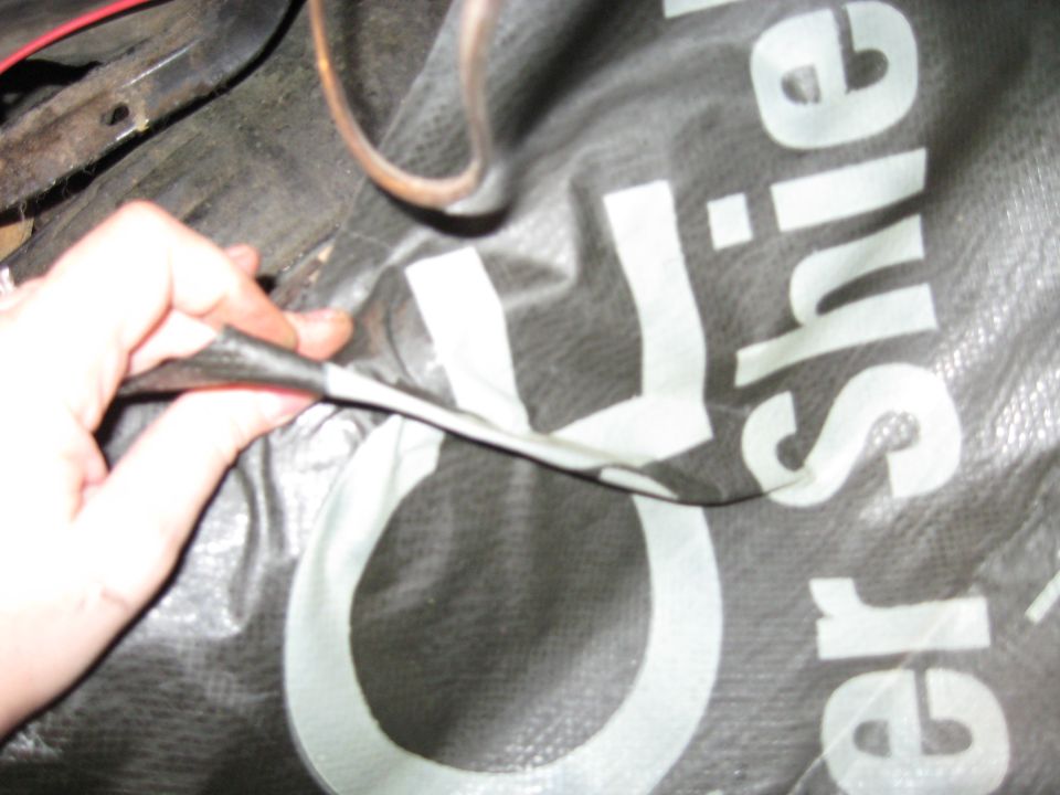 Black tarp with white lettering, partially held by a hand
