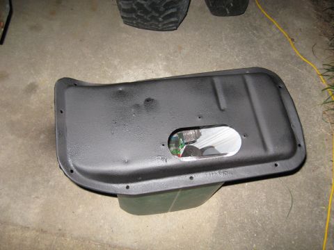 1978 Ford Bronco - Black metal part with an oval cutout showing internal electronics, placed on the ground.