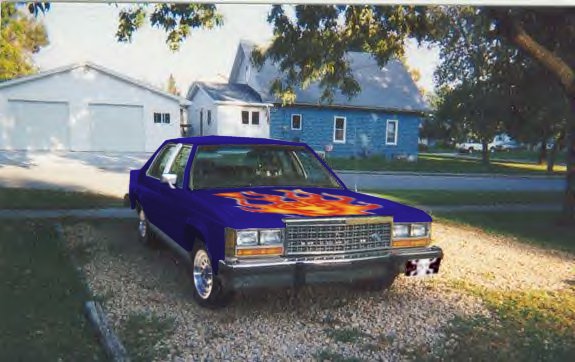 Blue Ford sedan with flame graphics parked on gravel by a house