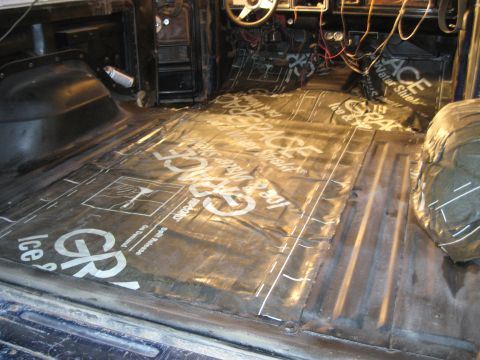 1978 Ford Bronco - The floor of a vehicle is covered with insulation material, revealing the dashboard and exposed wiring.