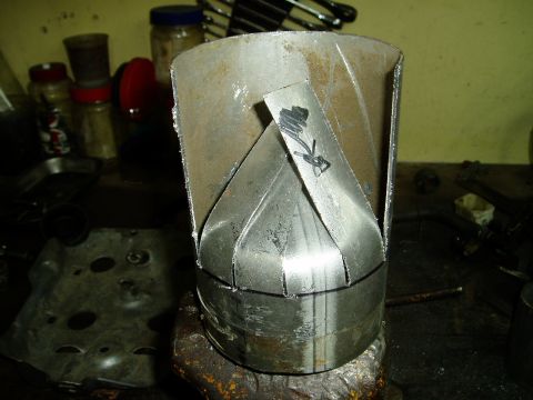 2000 Ford E350 - A custom-fabricated metal exhaust tip sits on a workbench, showing its unique internal design.