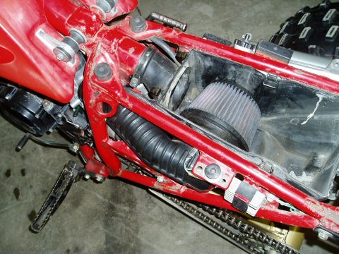 2000 Ford E350 - Close-up view of the engine compartment of a red vehicle, showing the frame, air filter, and other components.
