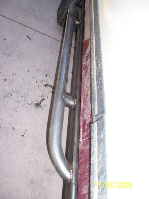 1991 Ford Bronco - A custom metal slider bar is attached to the side of a maroon vehicle, with a tire visible in the background.