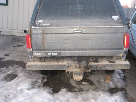 1990 Ford F-250 - The rear of a 1990 Ford F-250 pickup truck, equipped with a camper shell and a humorous bumper sticker.