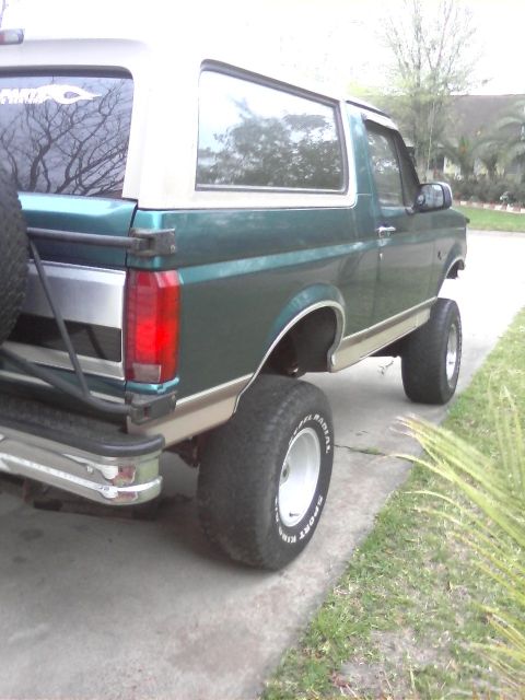 1996 Ford Bronco - Rear view of a lifted 1996 Ford Bronco with a two-tone paint scheme and a spare tire carrier.