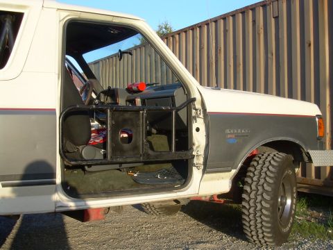 1991 Ford Bronco - Driver's side door open on a 1991 Ford Bronco, showing interior modifications and roll cage.