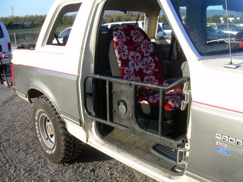 1991 Ford Bronco - The interior of a Ford Bronco features custom seat covers and a protective roll cage.