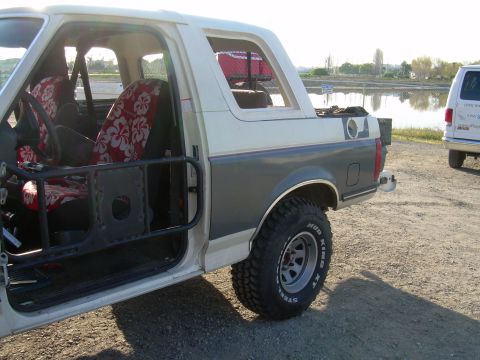 1991 Ford Bronco - This 1991 Ford Bronco features a two-tone paint scheme, custom interior with floral seat covers, and an external roll cage.