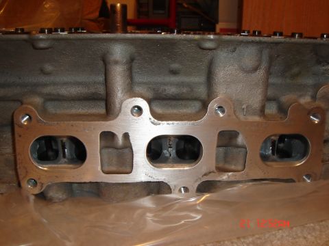 1993 Ford Probe - Close-up view of an engine cylinder head with an intake manifold gasket attached, revealing four intake ports.