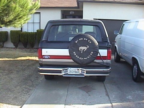 1990 Ford Bronco - The rear of a Ford Bronco is shown, a spare tire cover with the vehicle's name and brand.