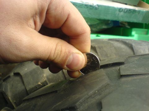 1985 Ford Bronco - Tire tread depth is being measured with a coin.