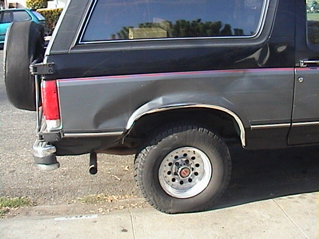 1990 Ford Bronco rear driver side with dent and flat tire