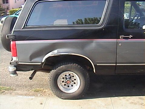 1990 Ford Bronco - This Ford Bronco shows extensive damage to its rear quarter panel and a flat tire.