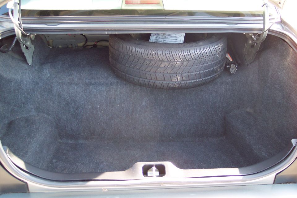 Empty car trunk showing the carpeted interior and a spare tire mounted on the right side
