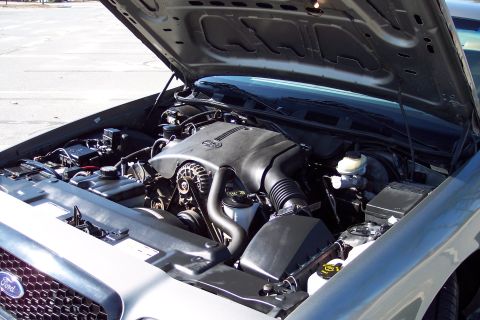 2001 Ford Crown Victoria - The engine bay of a 2001 Ford Crown Victoria is visible with the hood open, revealing the V8 engine and associated components.