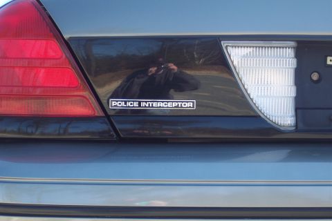2001 Ford Crown Victoria - The rear of a Ford Crown Victoria Police Interceptor is shown, a red taillight and a 'POLICE INTERCEPTOR' badge.