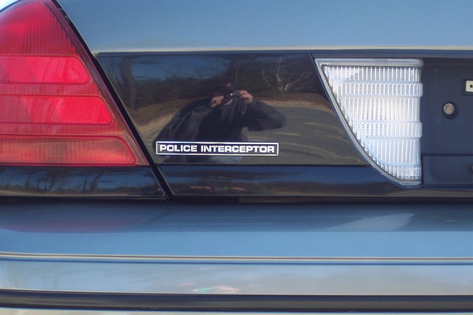 Rear of a 2001 Ford Crown Victoria Police Interceptor with a red taillight and a 'POLICE INTERCEPTOR' badge