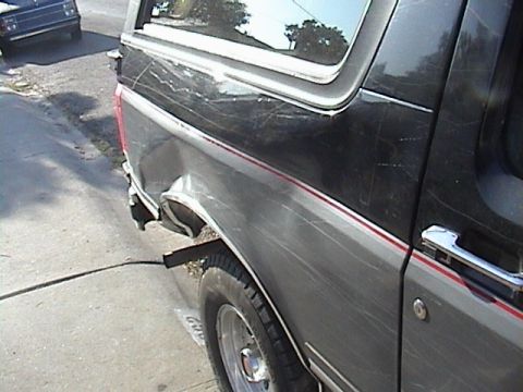 1990 Ford Bronco - This SUV has damage to its rear quarter panel and a red accent stripe along its side.