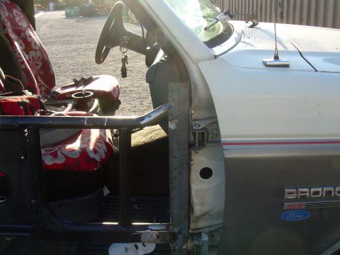 1991 Ford Bronco - The interior of a Ford Bronco shows custom roll cage modifications and patterned seat covers.