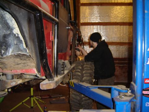 1992 Ford Bronco - A person works on a red off-road vehicle that is raised on a hydraulic lift in a garage.