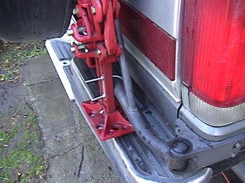 1990 Ford Bronco - A red hi-lift jack is mounted to the rear bumper of a vehicle, likely for off-road use.