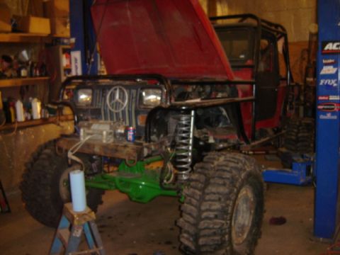 1992 Ford Bronco - This heavily modified off-road vehicle features a Mercedes-Benz emblem on its grille and its red hood is open.
