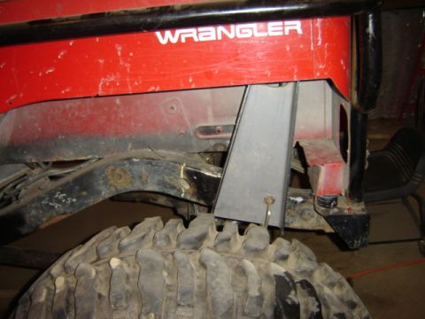1992 Ford Bronco - Close-up view of a red Jeep Wrangler's rear suspension and tire, with "WRANGLER" visible on the body panel.