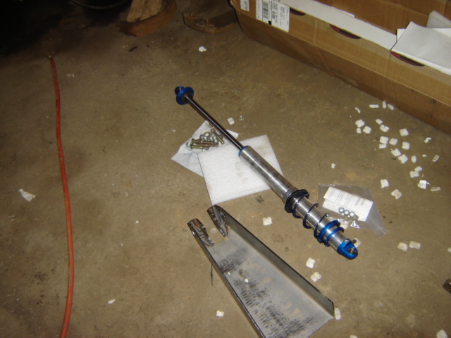 Shock absorber with blue accents and suspension part on concrete floor
