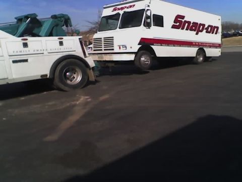 1992 Ford Bronco - A white Snap-on truck is parked next to a white tow truck on a paved surface under a blue sky.