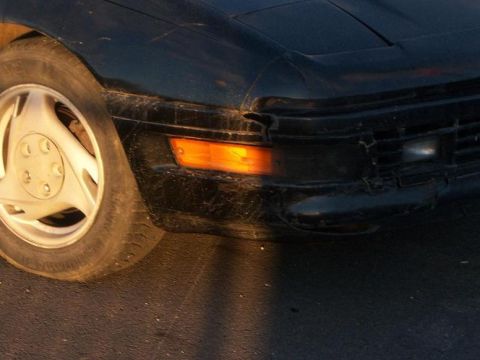 1990 Ford Probe - The front corner of a black car is visible, with a close-up on the wheel and turn signal.