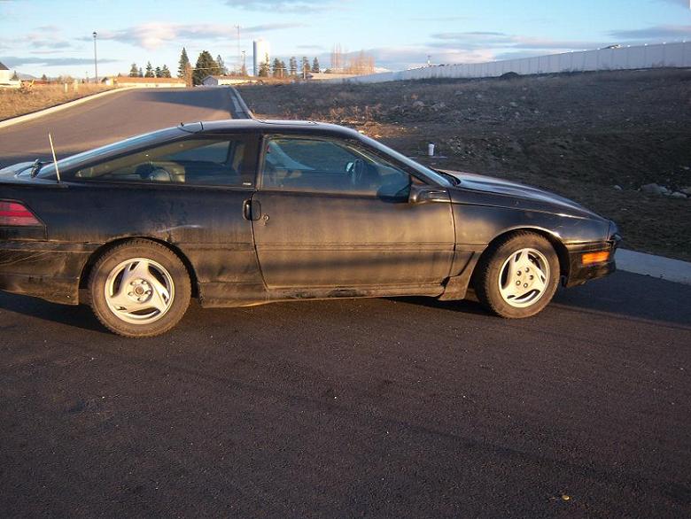 Black 1990 Ford Probe coupe, side view, dirty condition, parked on asphalt