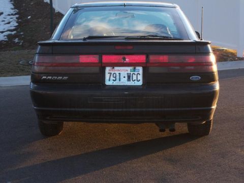 1990 Ford Probe - The rear of a dark coupe is visible, a 'PROBE' badge and a Washington license plate.