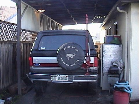 1990 Ford Bronco - Rear view of a 1990 Ford Bronco parked under a carport. Spare tire cover is visible.