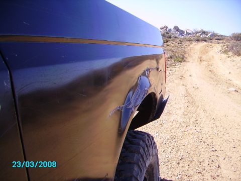 1990 Ford Bronco - Vehicle body damage visible on a dirt road with rocky hills in the background.