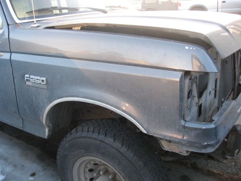1990 Ford F-250 - The front passenger side of a gray Ford F-250 shows damage, with the headlight assembly missing.