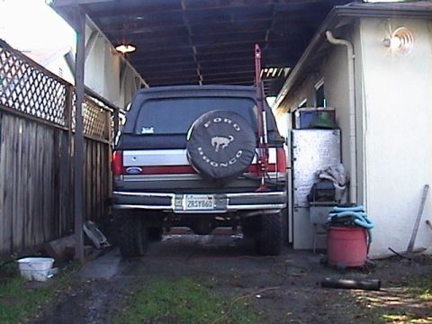 1990 Ford Bronco - This Ford Bronco is parked in a driveway with a spare tire cover and a Hi-Lift jack attached to the rear.
