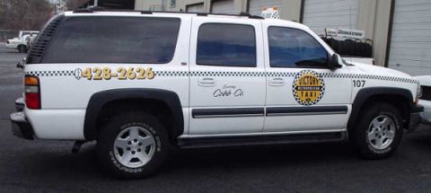 1996 Ford Crown Victoria - White Chevrolet Suburban taxi with "Victory Metropolitan Taxi" logo and phone number 428-2626 on the side.
