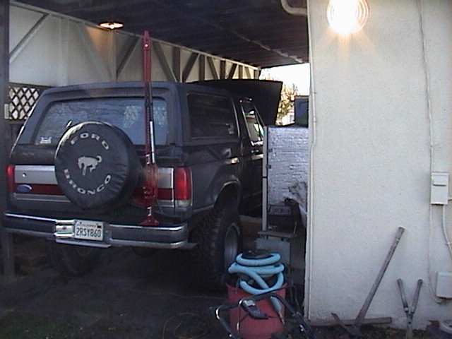Black Ford Bronco rear view with a spare tire cover and a Hi-Lift jack mounted