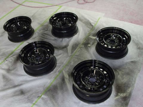 1996 Ford Crown Victoria - Several black steel wheels are laid out on a drop cloth, possibly for painting or refinishing.