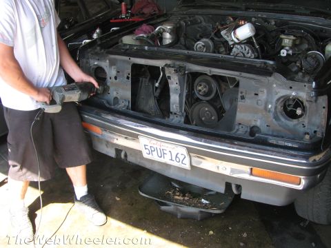 1987 Suzuki Samurai - A person uses a reciprocating saw on the front end of a 1987 Suzuki Samurai, revealing the engine during a V6 swap.